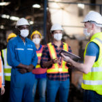 Foreman instructing technicians in a factory at start of shift