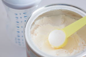 Milk powder for baby in measuring spoon on can.