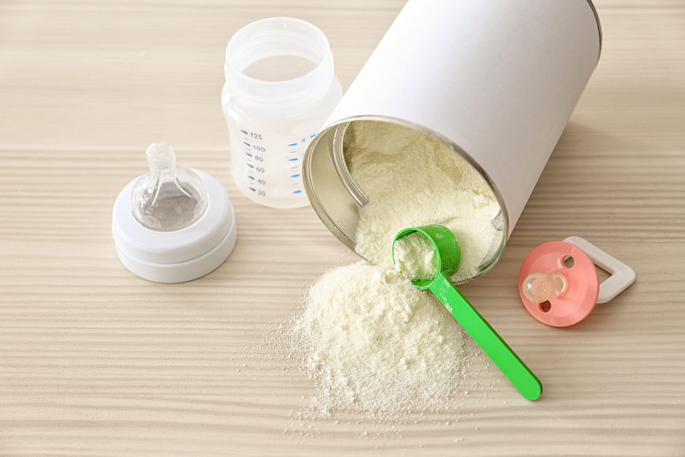 Stock Holders Sue Abbott for Fraud After Infant Formula Recall Feeding bottle with bank of baby milk formula on wooden background