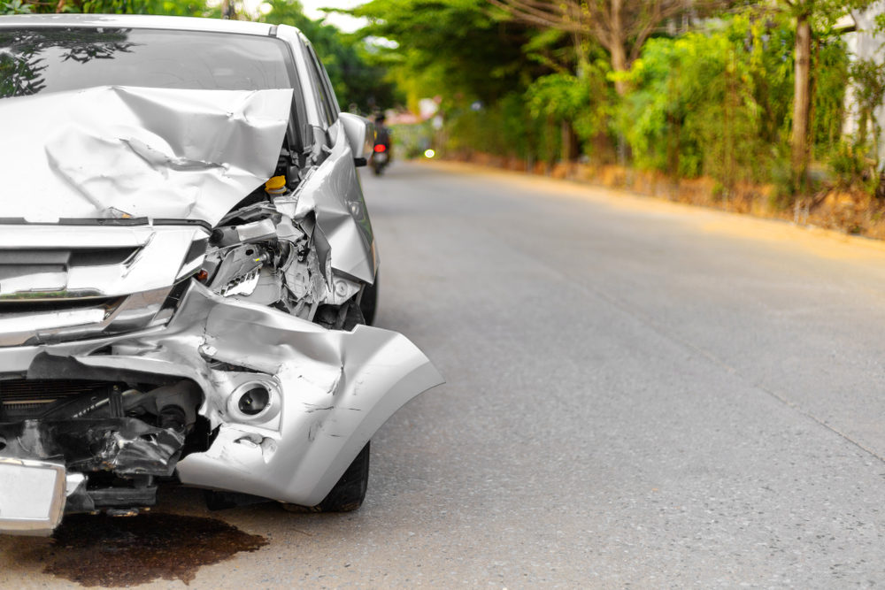 Front of light gray car big damaged and broken by accident on road parking can not drive any more.