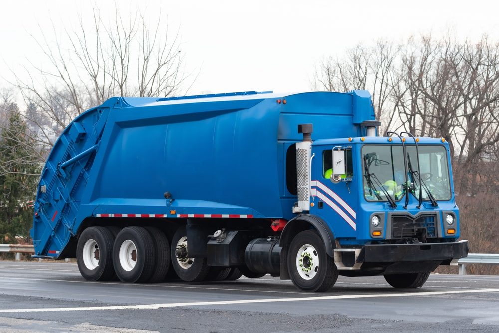view of blue garbage truck on roadway