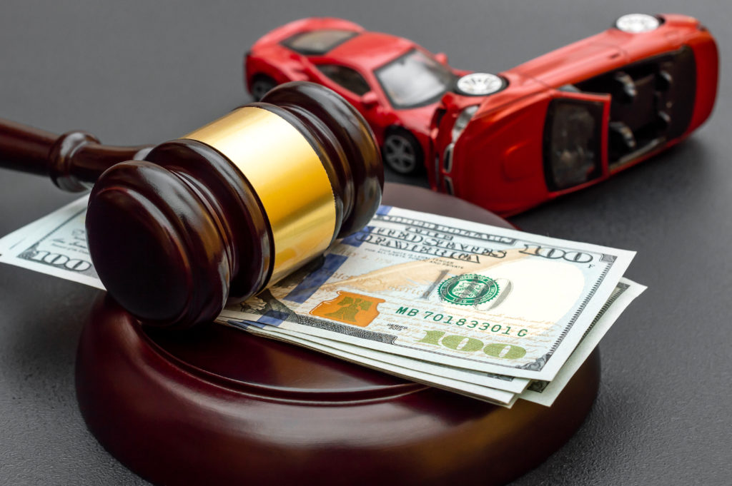 Texas Distracted Driving Is Not Only Dangerous But Costly Judge's gavel with money and toy cars on black.
