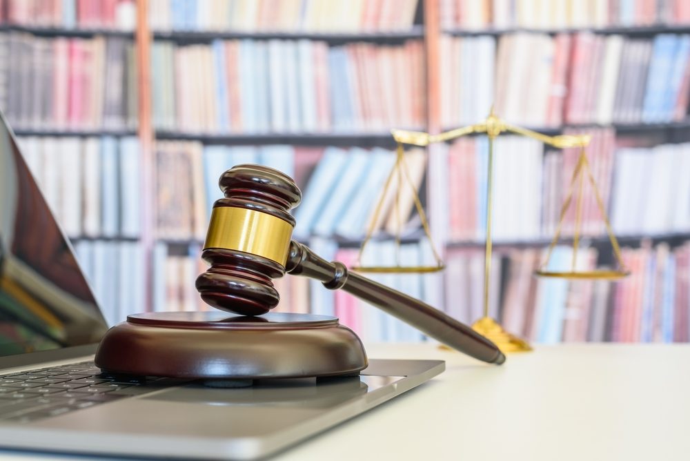 Judge gavel or a hammer and a base used by a judge person on a desk in a courtroom with blurred weight scale of justice.