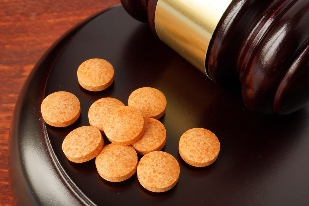 Zantac Manufacturers Face DOJ Probe Into Possible Fraud Charges Gavel and tablets on a wooden table.