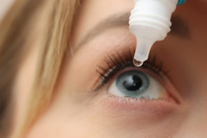 Young woman using eye drops