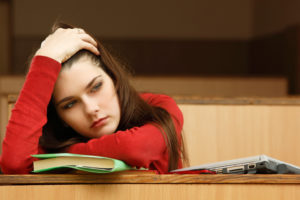student teen girl tired in empty classroom university