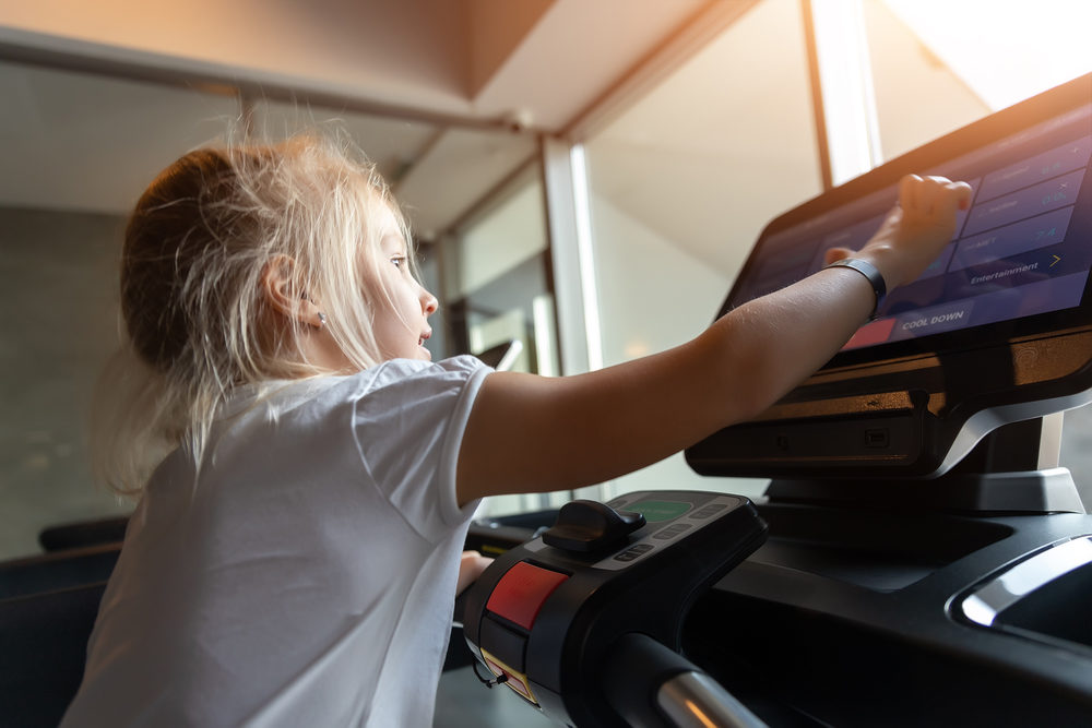 blond girl doing fitness exercise on treadmill machine in sport gym