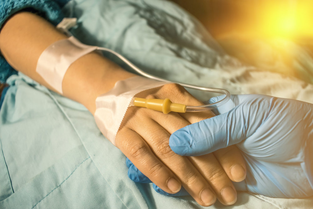 Doctor's gloved hand comforting cancer patient