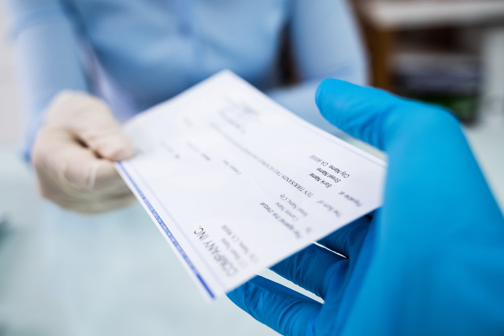 payroll check handed to employee wearing blue gloves