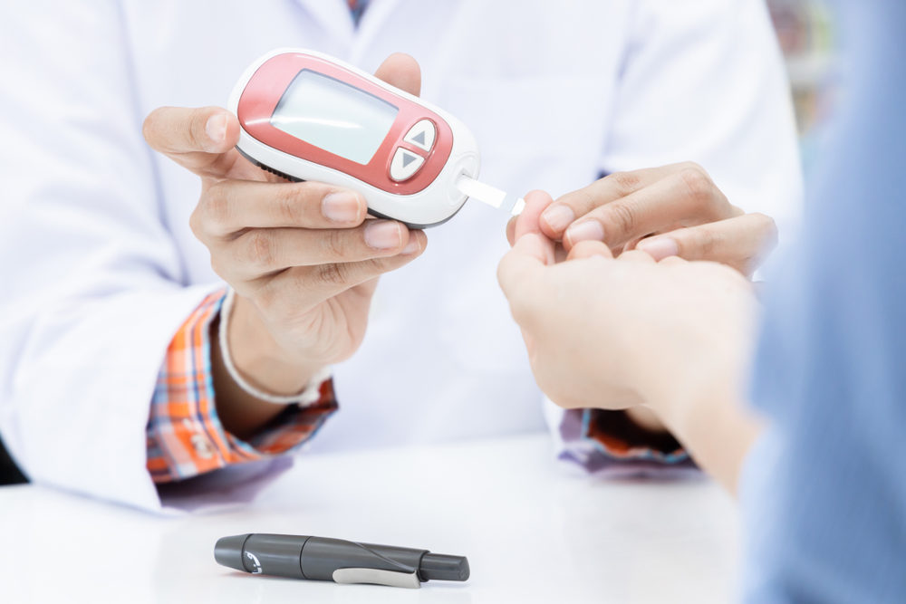 A doctor or pharmacist pricks a woman's finger to check her blood glucose level