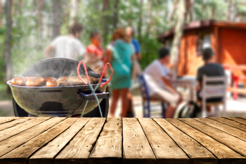 Grilling meat while family waits at campsite