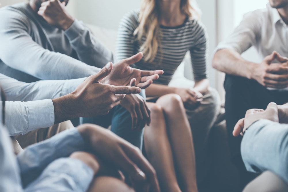  Close-up of people communicating while sitting in circle and gesturing