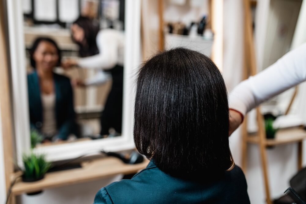 An middle aged African American woman after a curly hair straightening treatment at a hair salon.