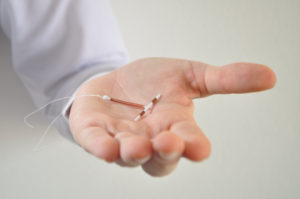 Holding an IUD birth control copper coil device in hand