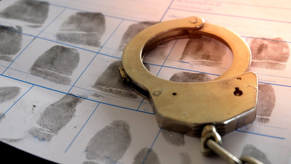 A metal handcuff sitting on a fingerprint file