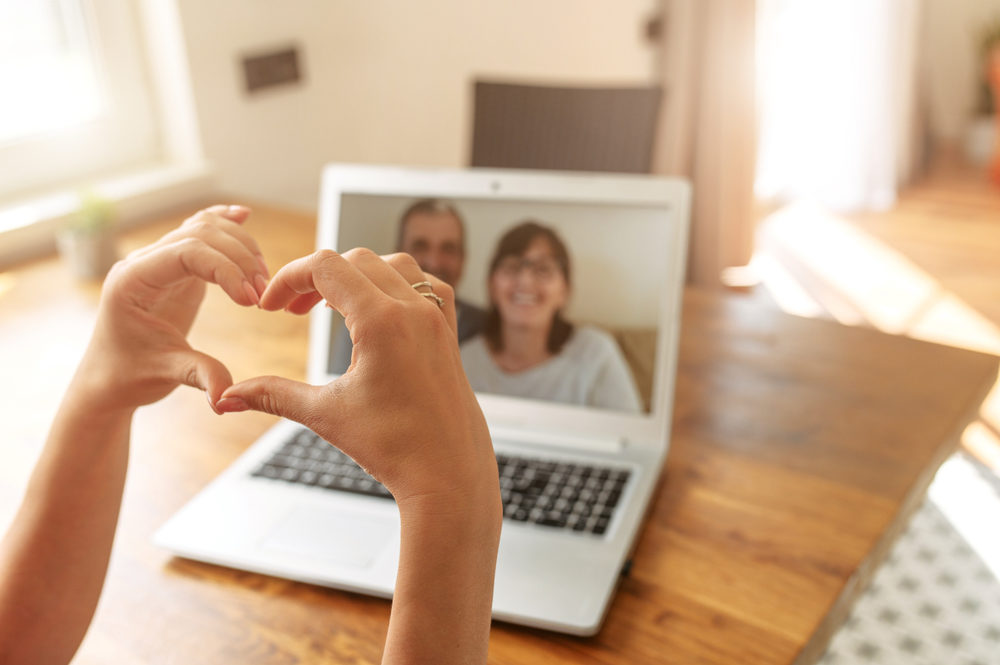  Female hands are showing heart shape to parents on the laptop
