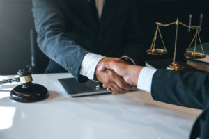 Businessman shaking hands to seal a deal with his partner lawyers or attorneys discussing a contract agreement.