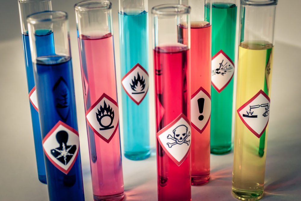 Hazardous chemicals of many colors in test tubes with warning labels