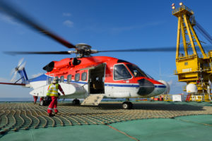 The helicopter landing officer is going to helicopter at oil rig platform