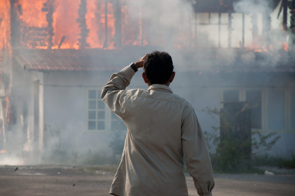 man looking at house on fire