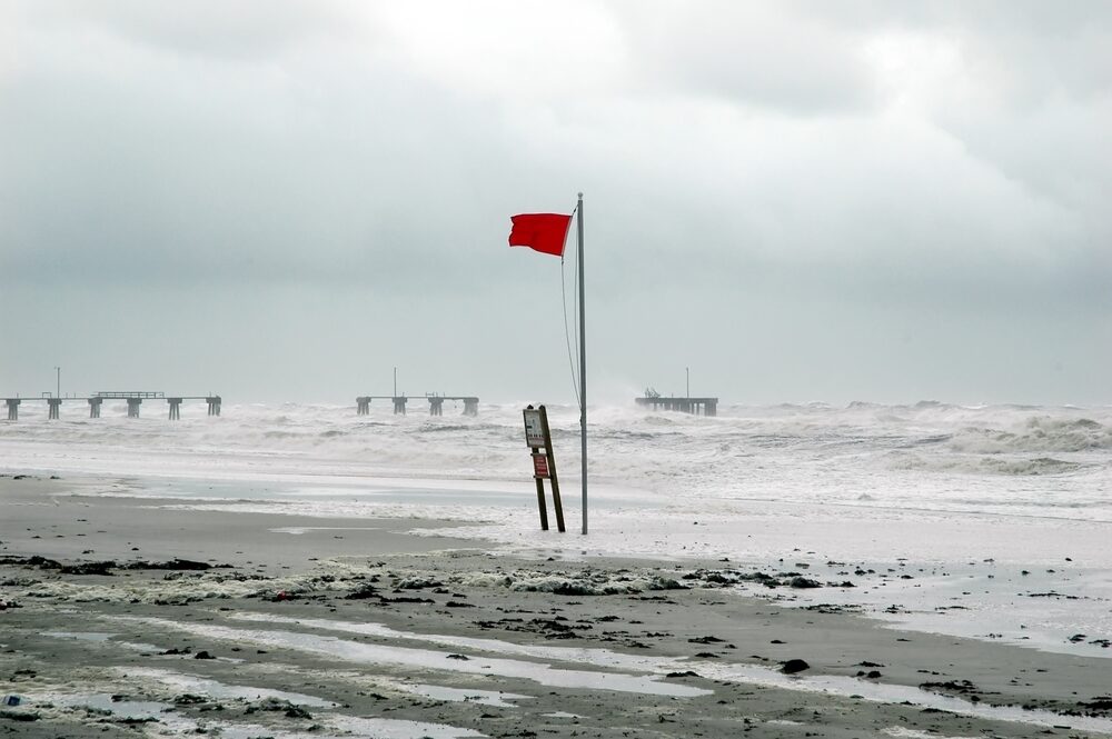 red flag flying at beach warning of oncoming hurricane
