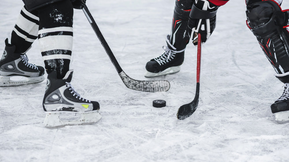 Two players try to get the puck on the ice at a hockey game