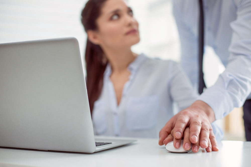 young woman sitting at the table and working while feeling a male hand on hers