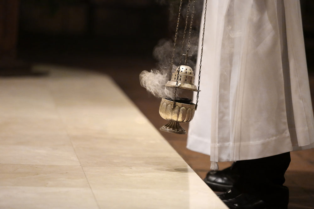 Altar boy holds incense during mass at the altar of a catholic church