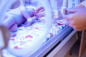  mother hands caressing and touching her new born baby in intensive care unit in a incubator
