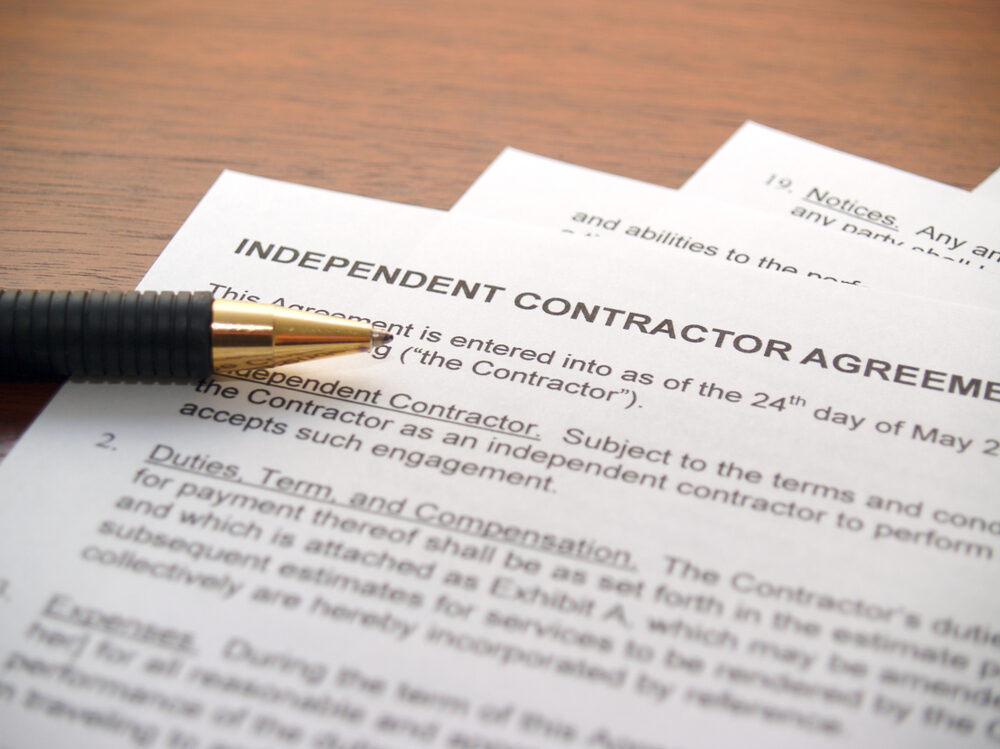 a pen laying on an independent contractor agreement at desk