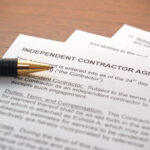 a pen laying on an independent contractor agreement at desk