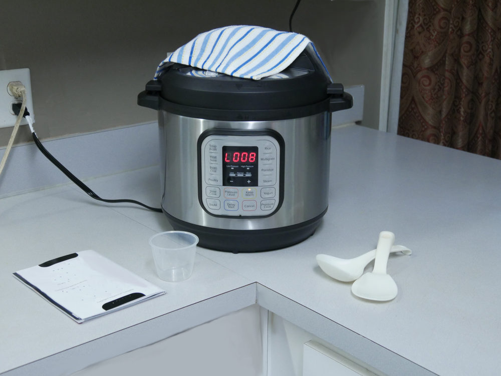 Instant pot on a countertop with a towel resting on top