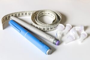 insulin injector pens and cartridges on a white table with a tape measure