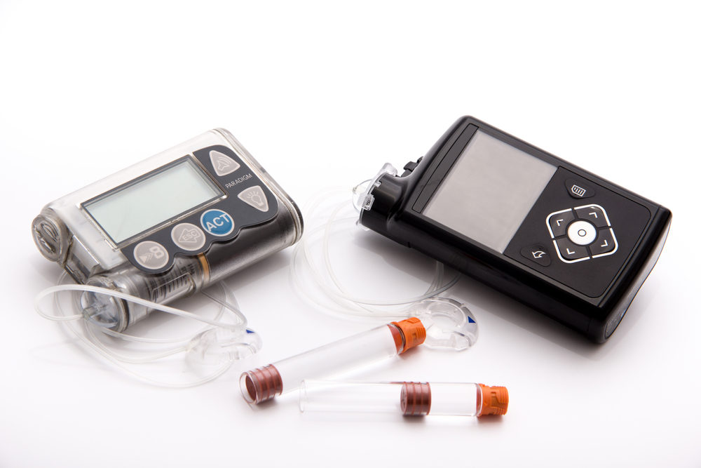Two different insulin pumps on white table with white background