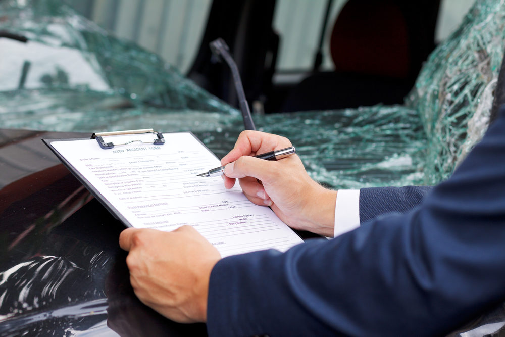 Well dressed insurance adjuster inspecting damaged vehicle