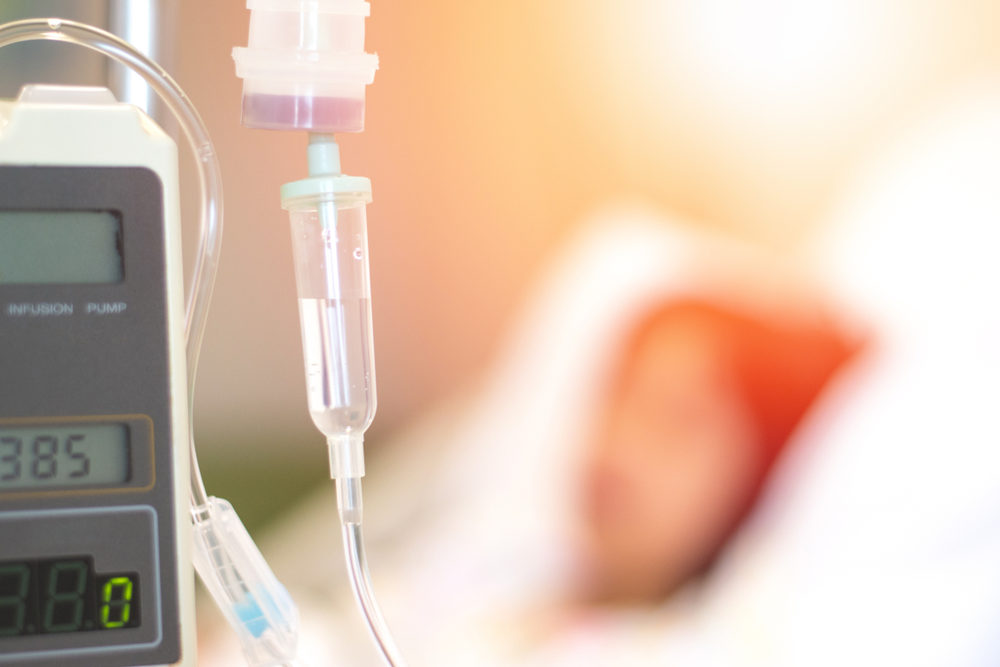 IV infusion pump tube set with blur patient on bed in clinical hospital