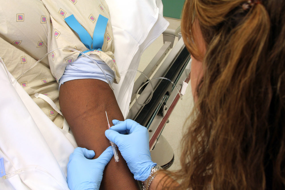 An emergency room nurse starts an IV, intravenous line, on a patient in need of help.  