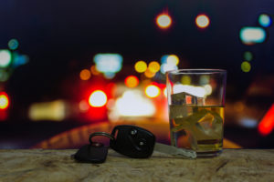 keys and an alcoholic beverage with car lights in background