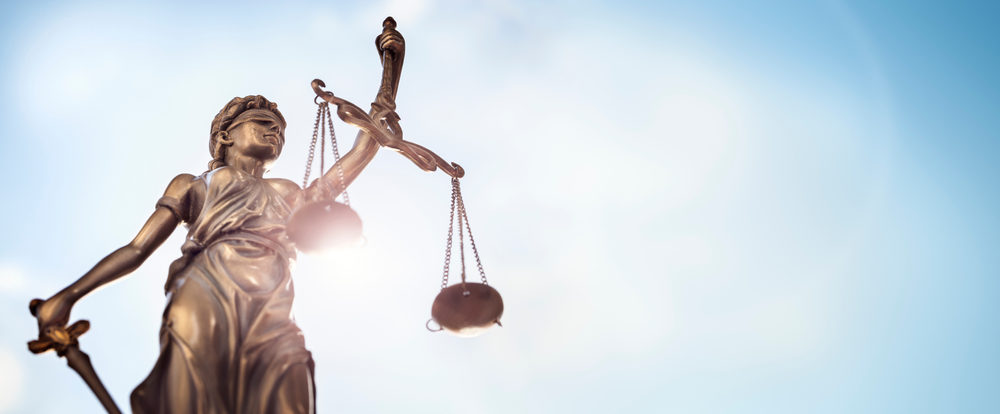 statue of Lady Justice with scales of justice and sky background