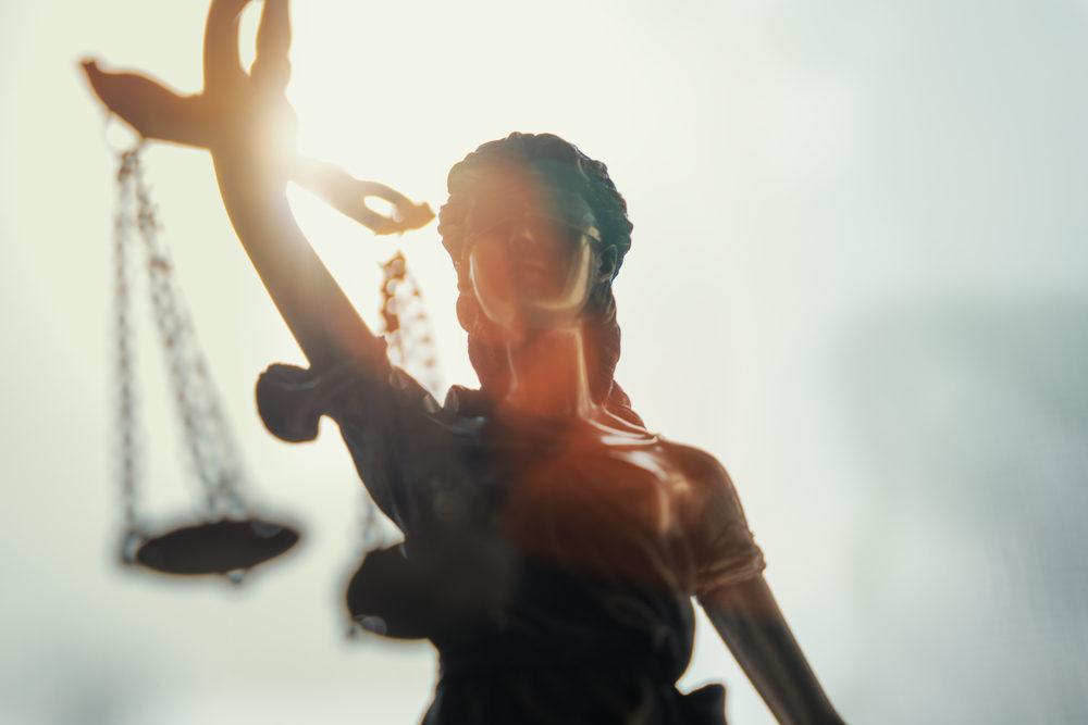 Statue of lady justice with sunlight shining behind