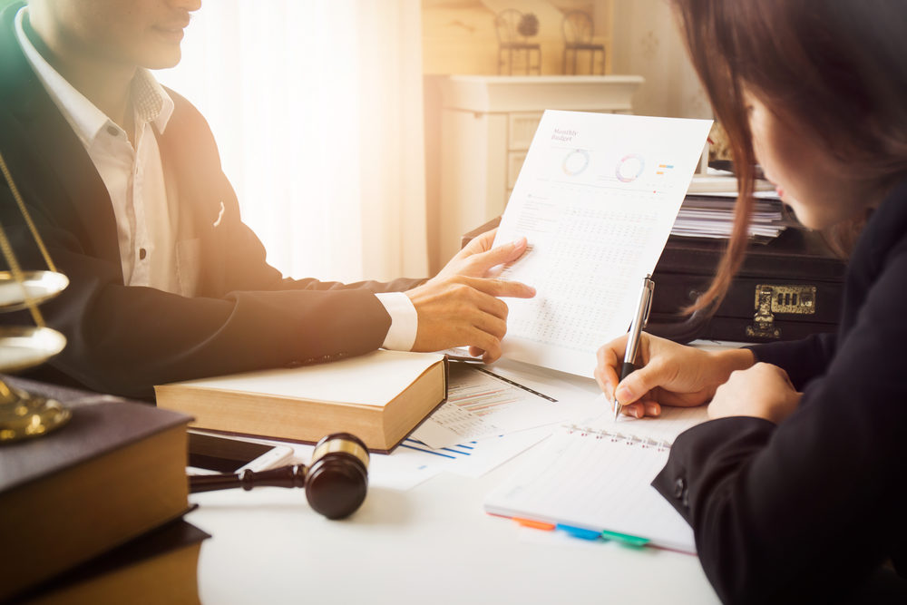 male attorney consulting a female client at desk in office.