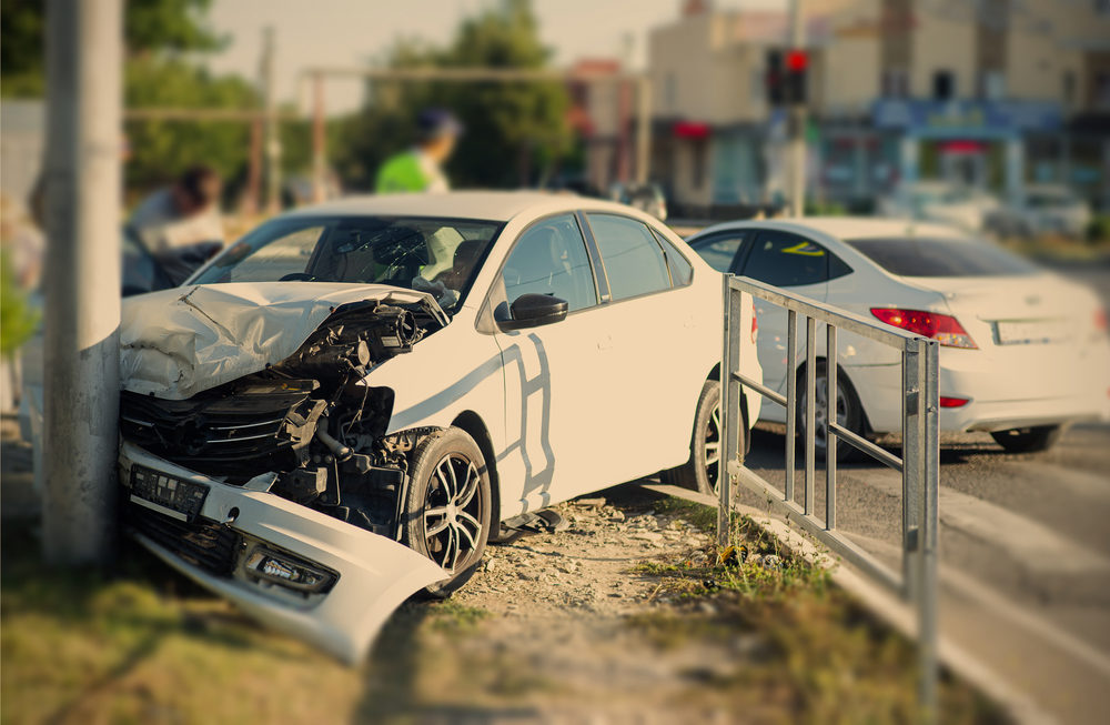 white car crashed into a light post on a city street