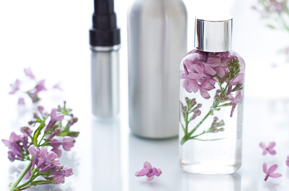 Cosmetic bottle close up with lilac flowers