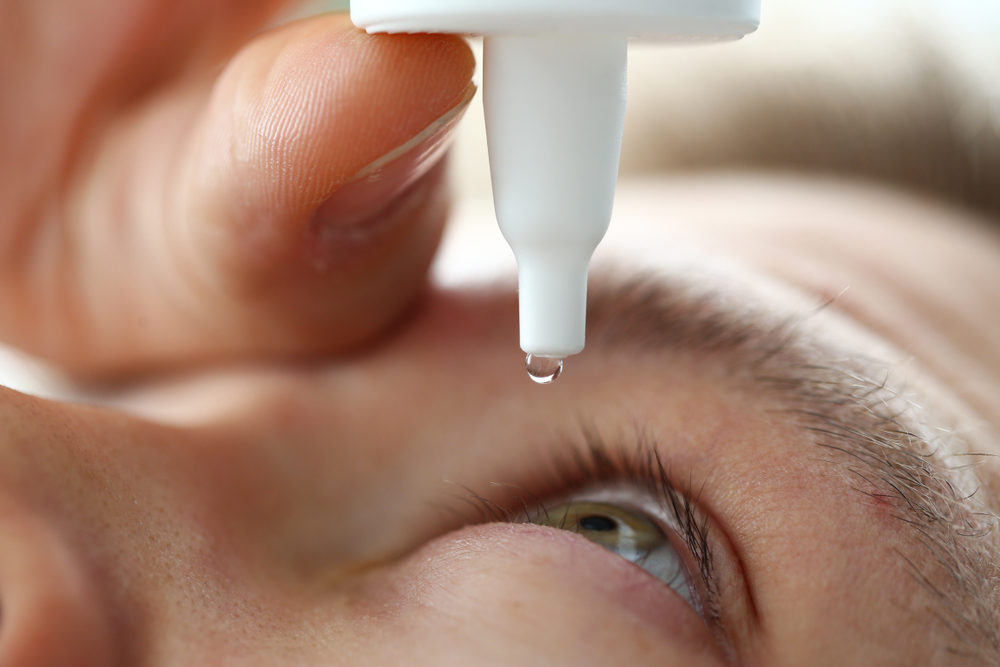 FDA Announces Recalls of Two More Types of Eye Drops Due to Fears of Contamination Male hand putting liquid drops in his eye solving vision problem closeup