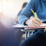 male student completing an exam at desk in school