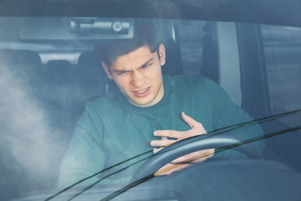 Young man suffering from chest pain sitting in car