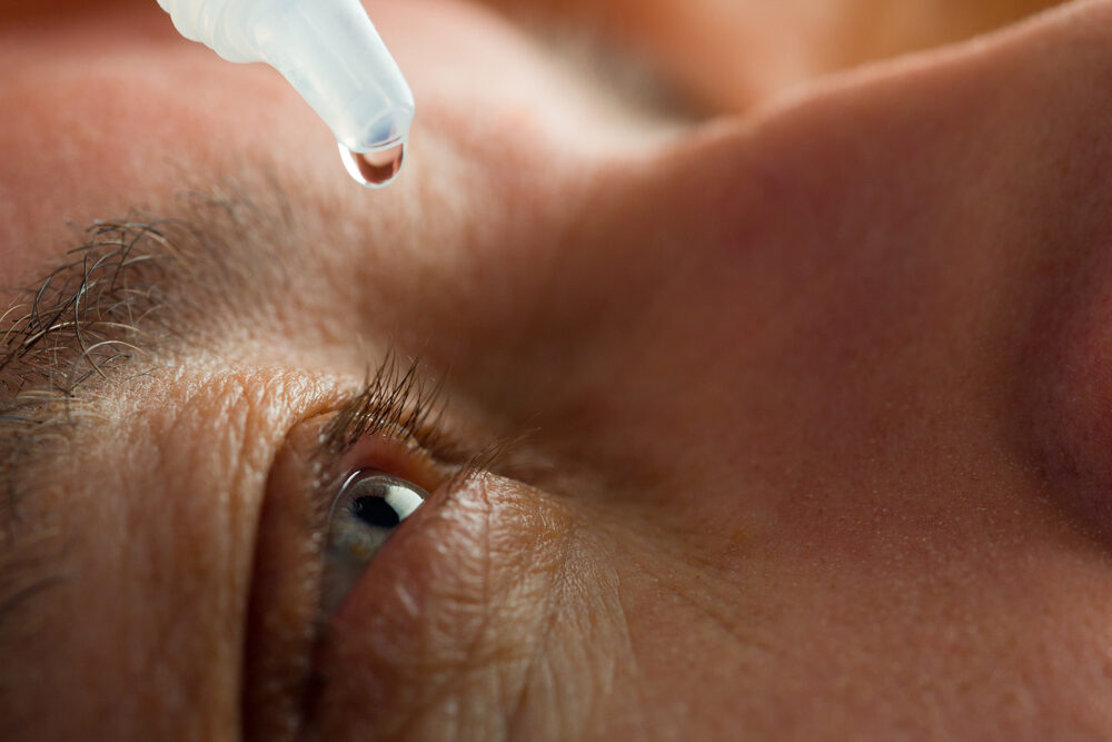 Minnesota Man Suffers Eye Infection After Using EzriCare Artificial Tears closeup of a man putting eye drops in his eyes