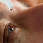 closeup of a man putting eye drops in his eyes