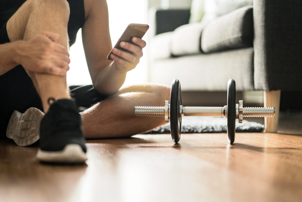 Man using smartphone during workout at home.