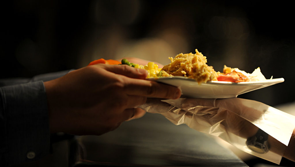 Gloved hands passing a plate full of food